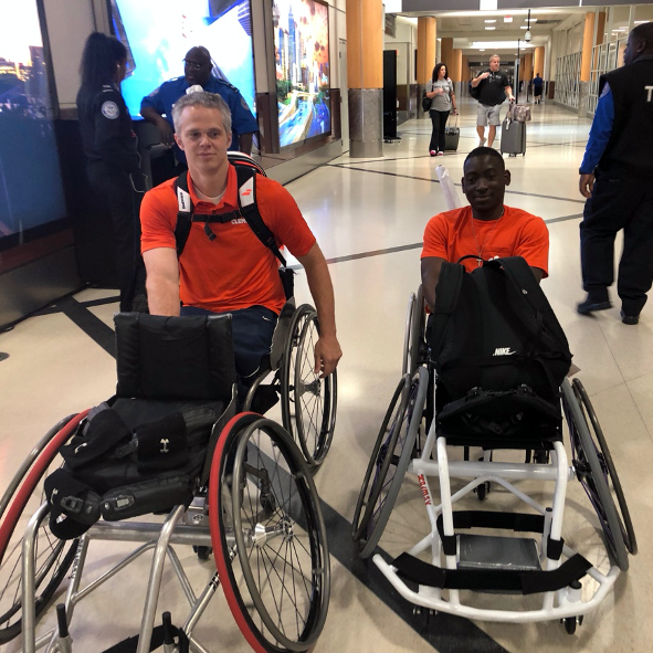this photo shows tennis wheelchair athletes Jeff Townsend and Marsden Miller of Clemson University trying to navigate an escalator with four wheelchairs