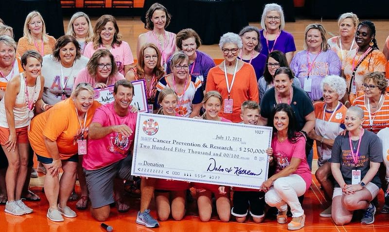 this photo shows Clemson Head Coach Dabo Swinney and his Dabo's All In Team Foundation presenting a check for $250,000 for breast cancer research.