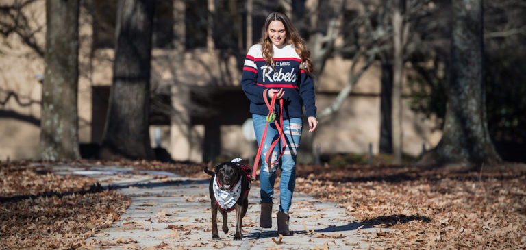 Lauren Graham is pictured walking her emotional support dog, a black Labradore retriever, on the University of Mississippi campus
