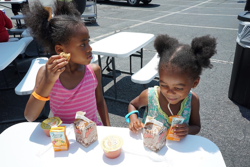 this photo shows two adorable little black girls enjoying a free meal from No Kid Hungry