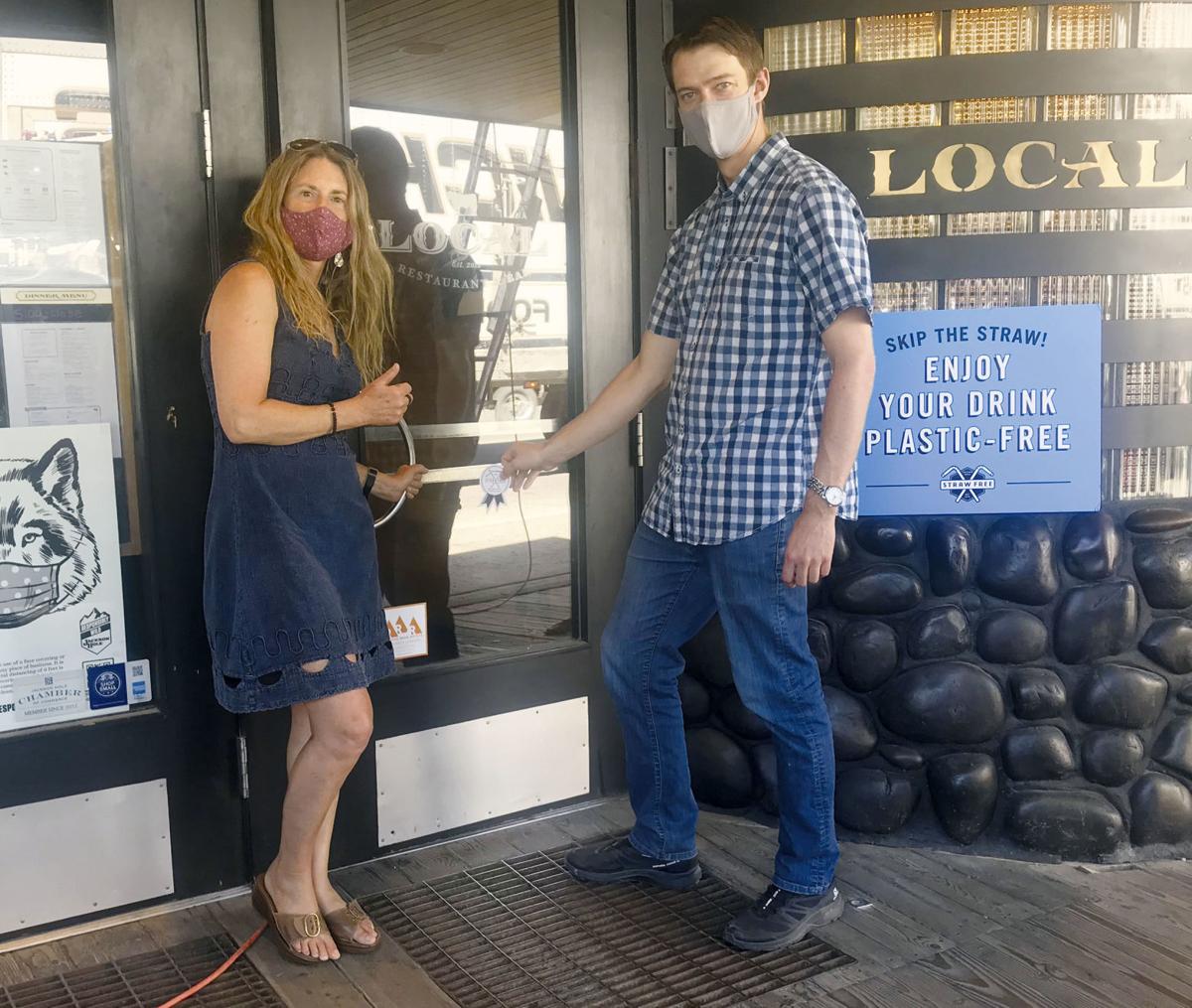 julie deardorff and josh hirschmann of Local Restaurant and Bar pose in front of the restaurant's door where a plastic-free sticker has been placed.