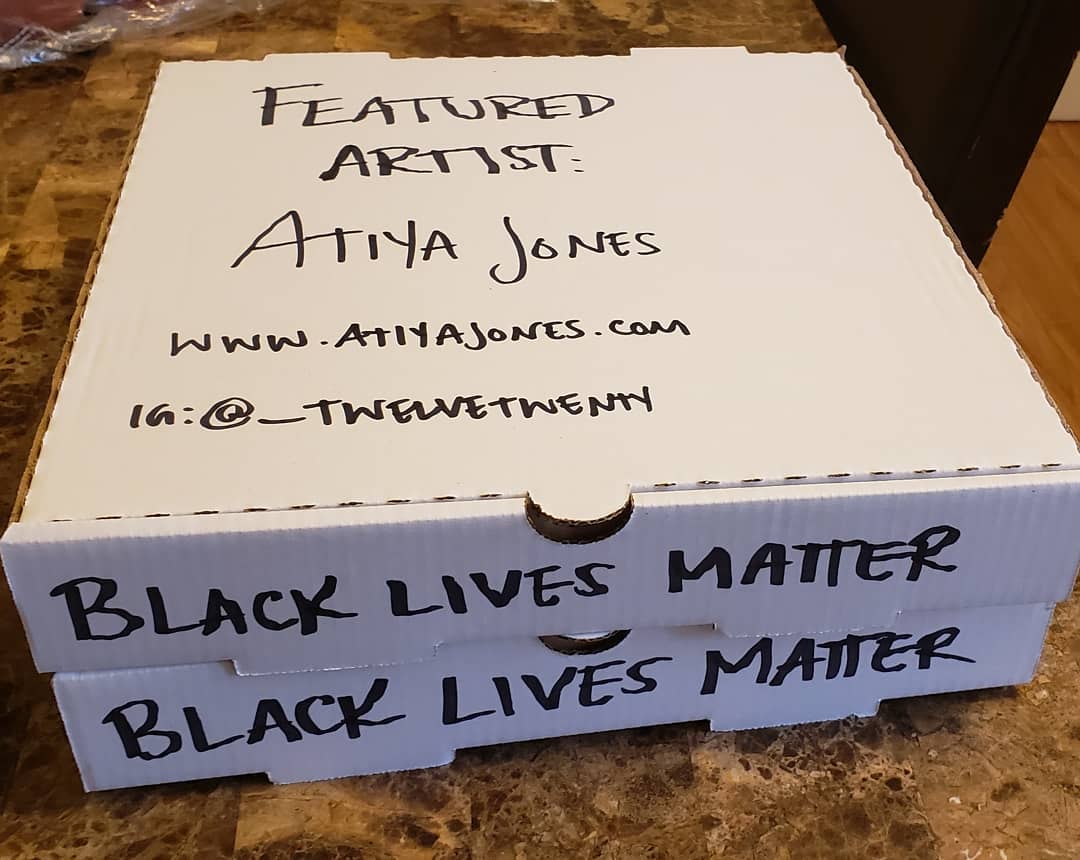 this photo shows a pizza box promoting artist Atiya Jones for the Social Justice Pizza Project