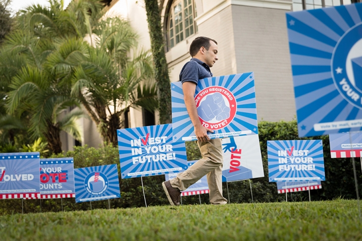 this photo shows a student putting out voter registration signs on the Rollins College campus for the Democracy Project