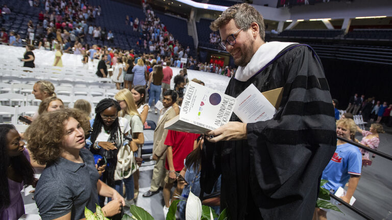 Author John Green signs a book for a student at the University of Mississippi's fall convocation.