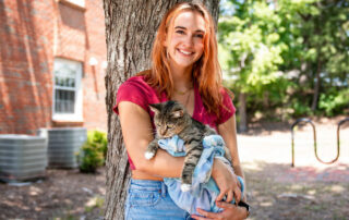 this photo shows a Campbell University student posing with her cat at Pet Hall.