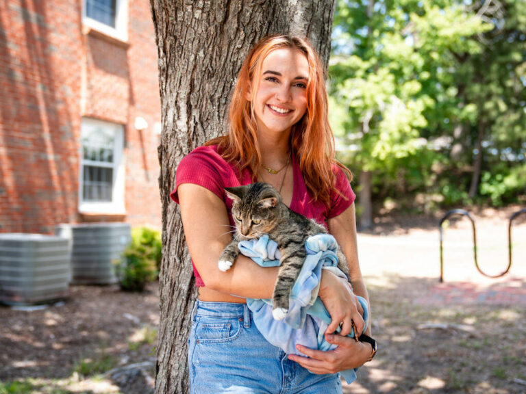 this photo shows a Campbell University student posing with her cat at Pet Hall.